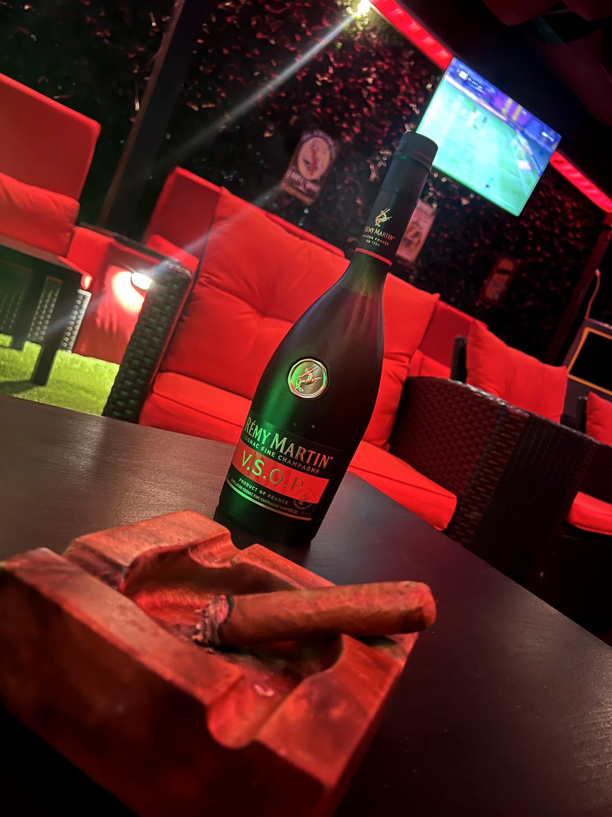 A cigar resting on an ashtray next to a bottle of cognac at 324 Cigar Lounge