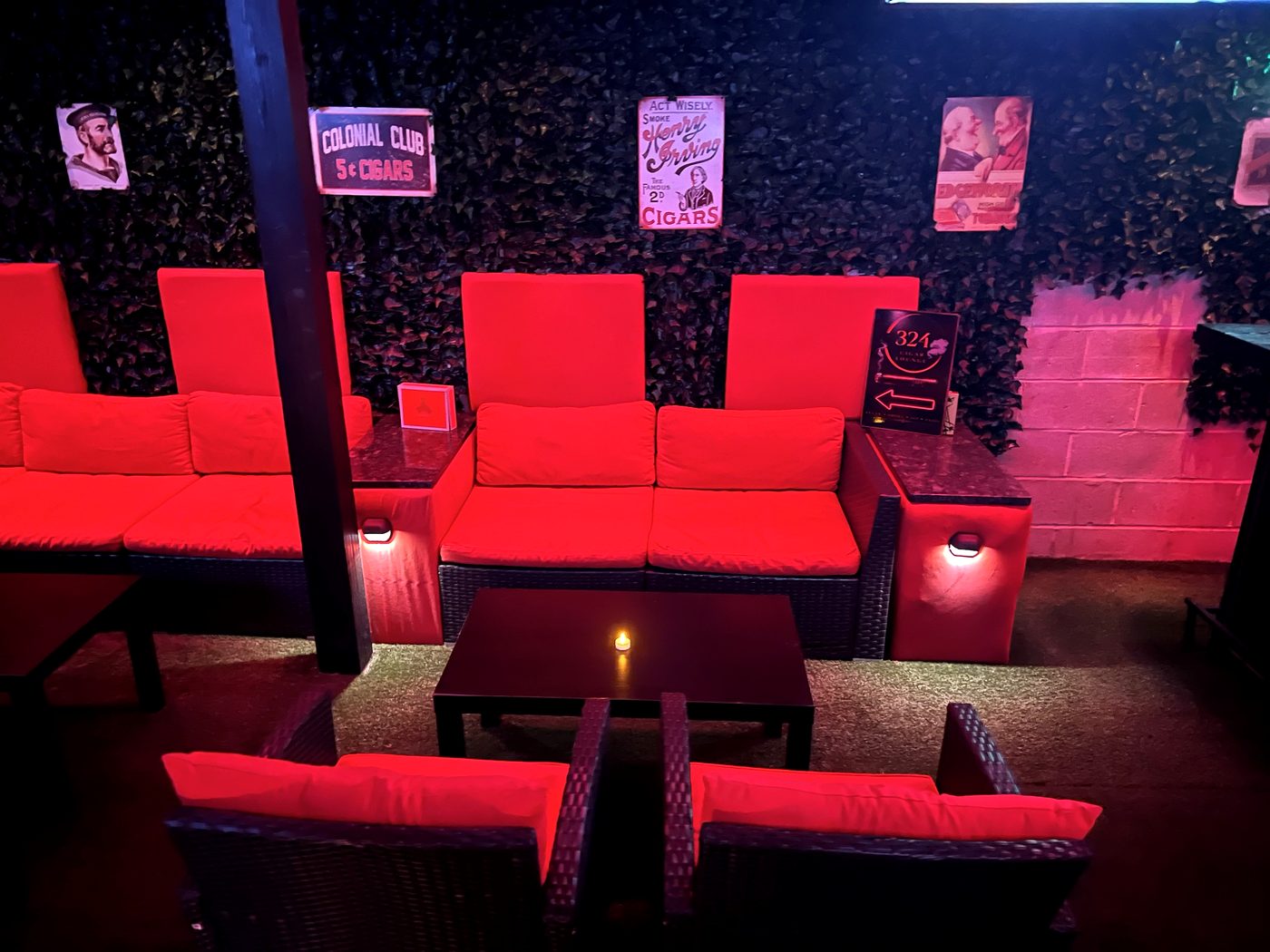 Long red sofa with candles and vintage cigar signs on the wall
