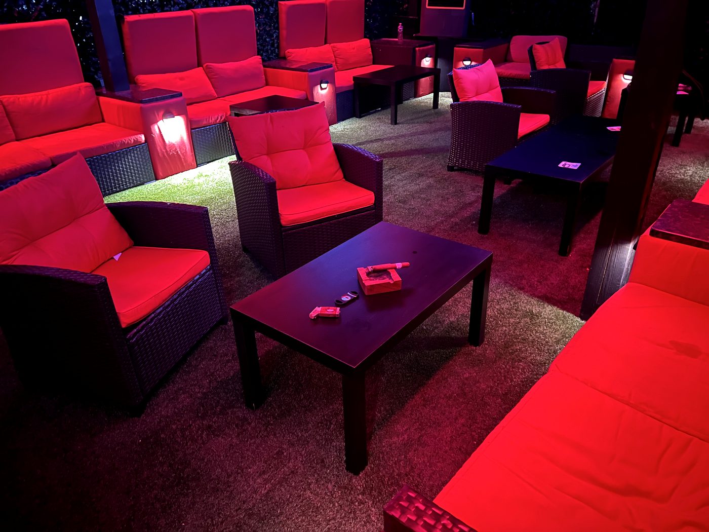 Lounge tables with ashtrays between deep red armchairs